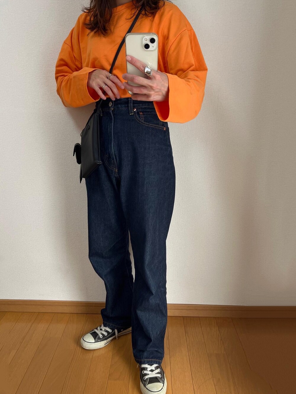 オレンジ系のTシャツ/カットソー、ブルー系のデニムパンツ、ブラック系のショルダーバッグを着用したレディースの秋コーディネートの2枚目の写真