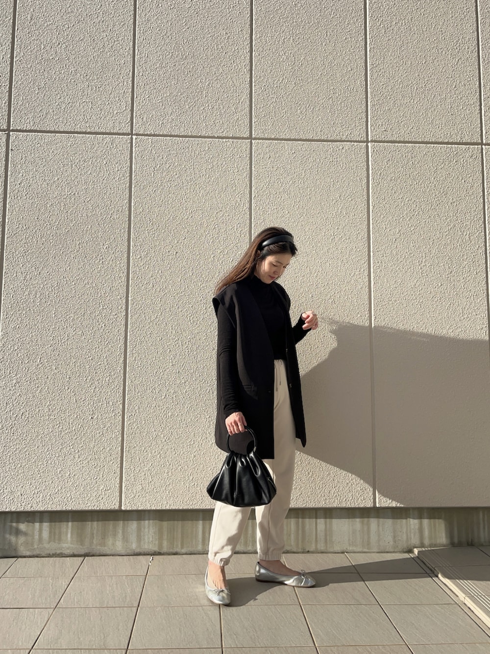 ホワイト系のスウェットパンツ、ホワイト系のニット/セーター、ブラック系のベストを着用したレディースの秋コーディネートの2枚目の写真