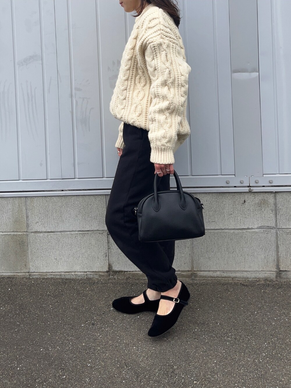 ブラック系のスウェットパンツ、ホワイト系のニット/セーター、ブラック系のパンプスを着用したレディースの冬コーディネートの2枚目の写真