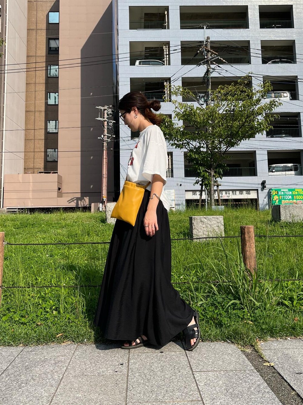 イエロー系のショルダーバッグ、ホワイト系のTシャツ/カットソー、ブラック系のスカートを着用したレディースの秋コーディネートの2枚目の写真