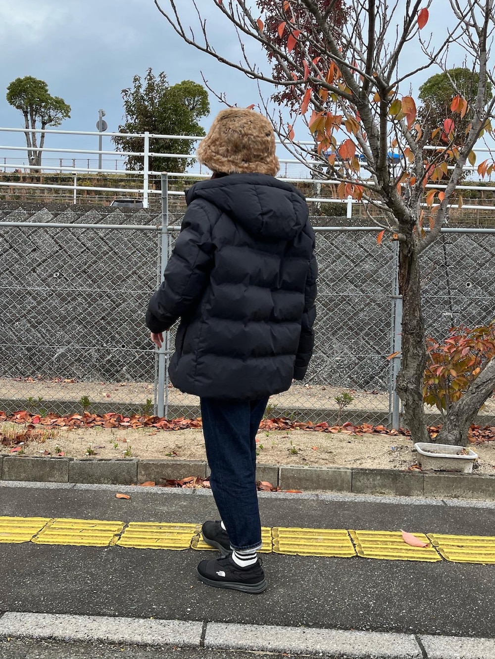 ブラック系のスニーカー、ブラック系のTシャツ/カットソー、ブルー系のデニムパンツを着用したレディースの冬コーディネートの2枚目の写真