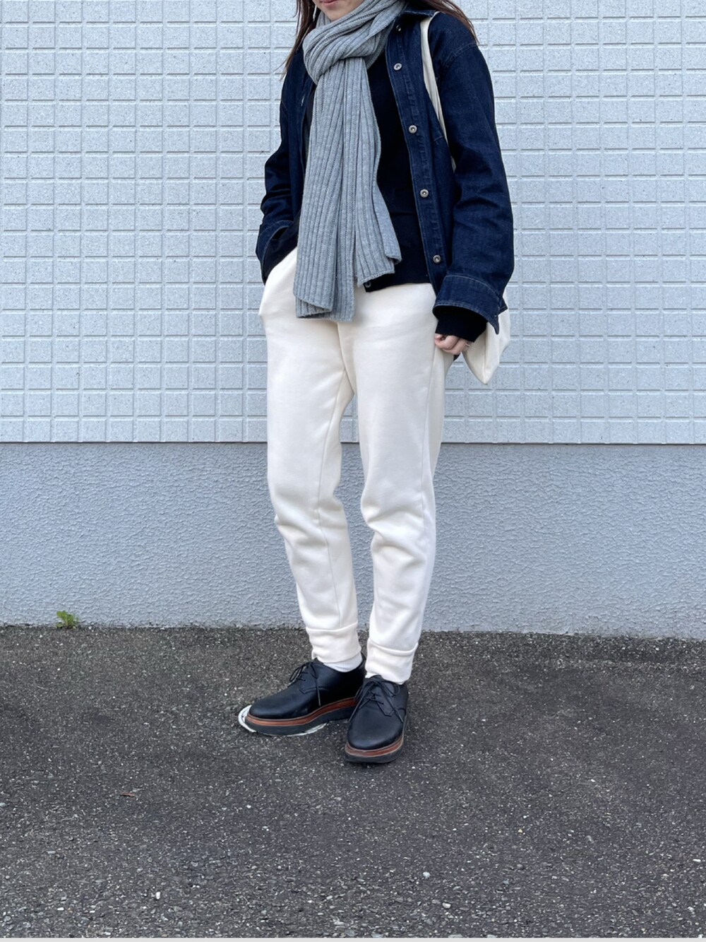 ホワイト系のスウェットパンツ、ブルー系のデニムジャケット、レッド系のトートバッグを着用したレディースの冬コーディネートの2枚目の写真