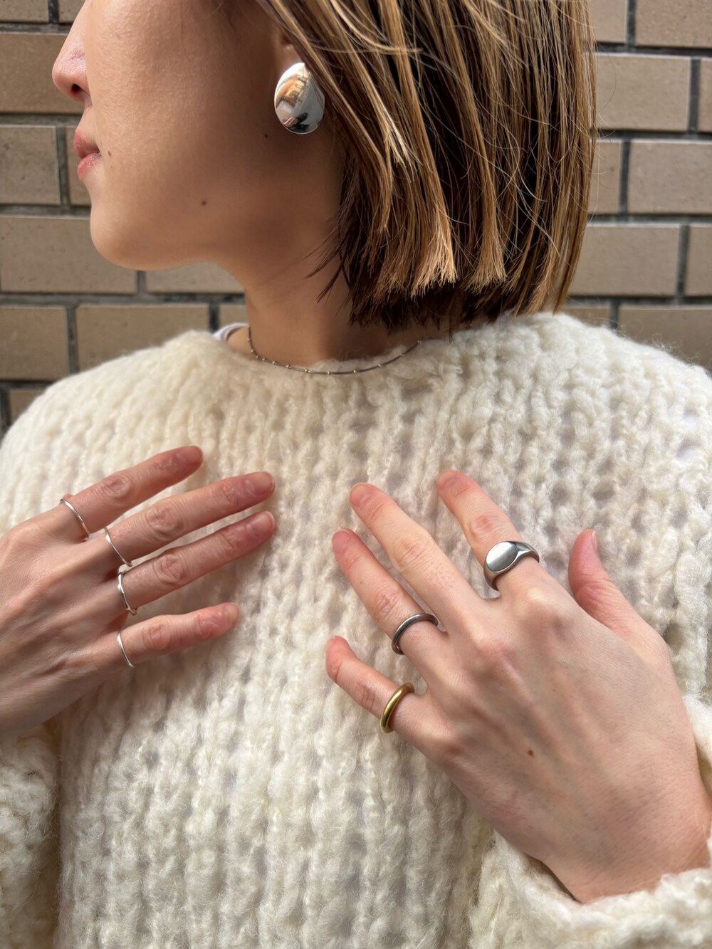 ホワイト系のニット/セーター、ホワイト系のチノパンツ、グレー系のサンダルを着用したレディースの冬コーディネートの3枚目の写真