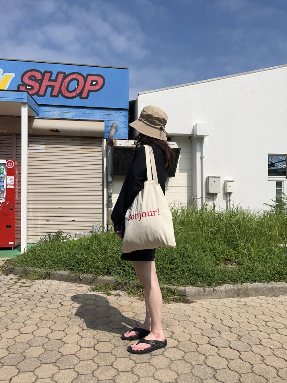 ブラック系のサンダル、ベージュ系のハット、ブラック系のラッシュガードを着用したレディースの夏コーディネートの3枚目の写真