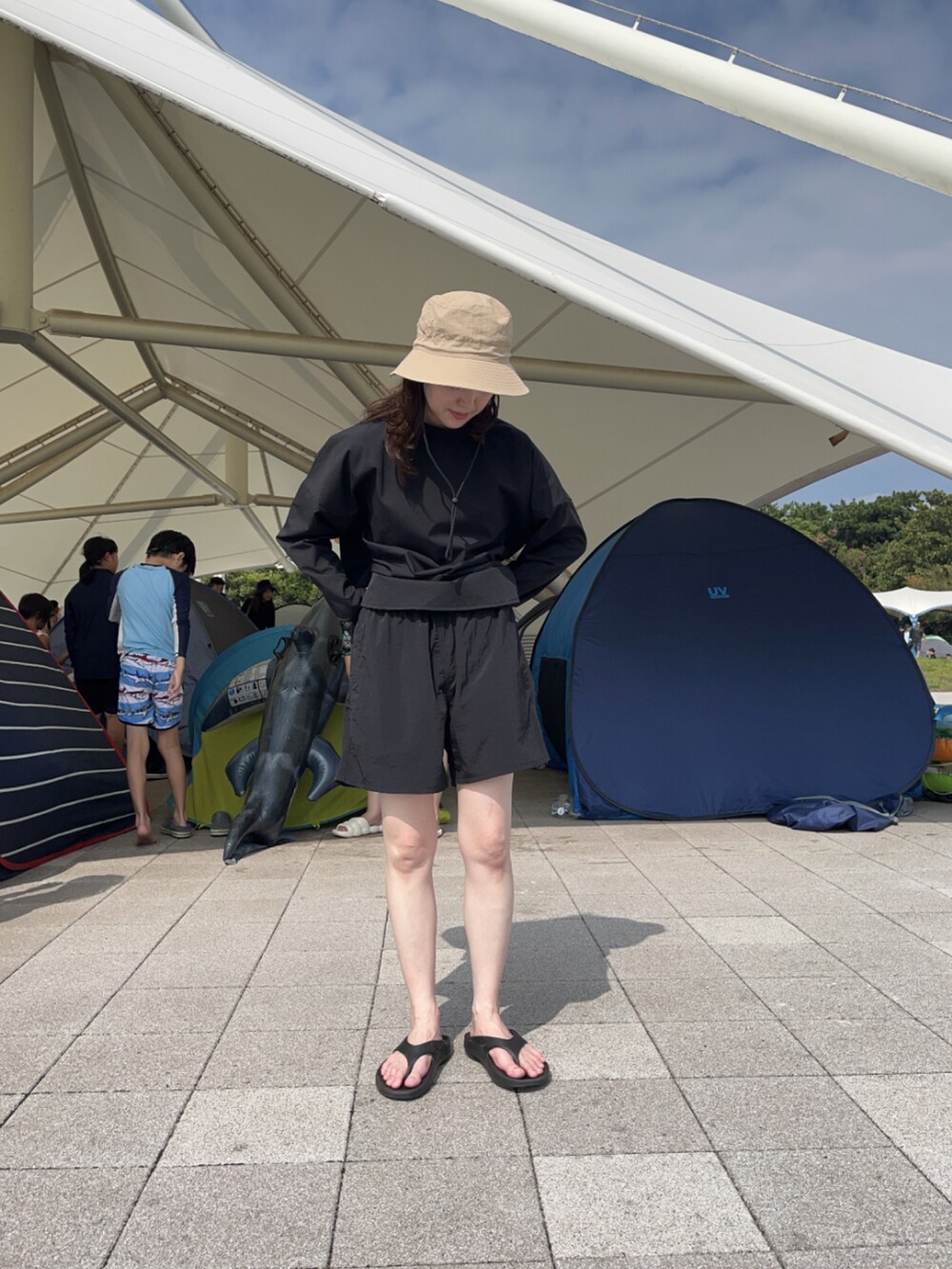 ブラック系のサンダル、ベージュ系のハット、ブラック系のラッシュガードを着用したレディースの夏コーディネートの2枚目の写真