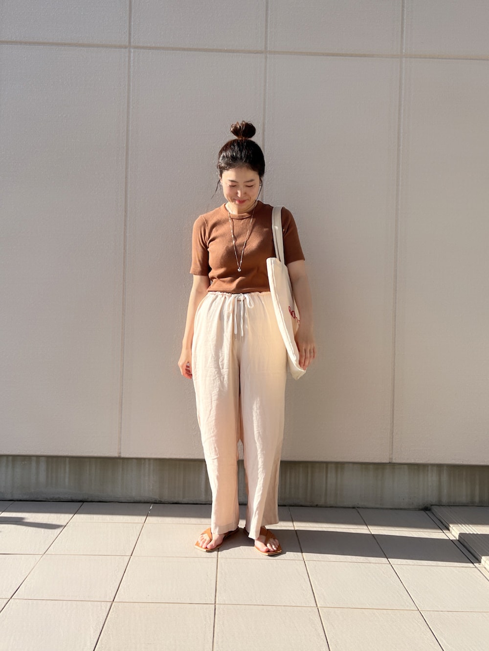 ブラウン系のトップス、イエロー系のサンダル、レッド系のトートバッグを着用したレディースの秋コーディネートの2枚目の写真