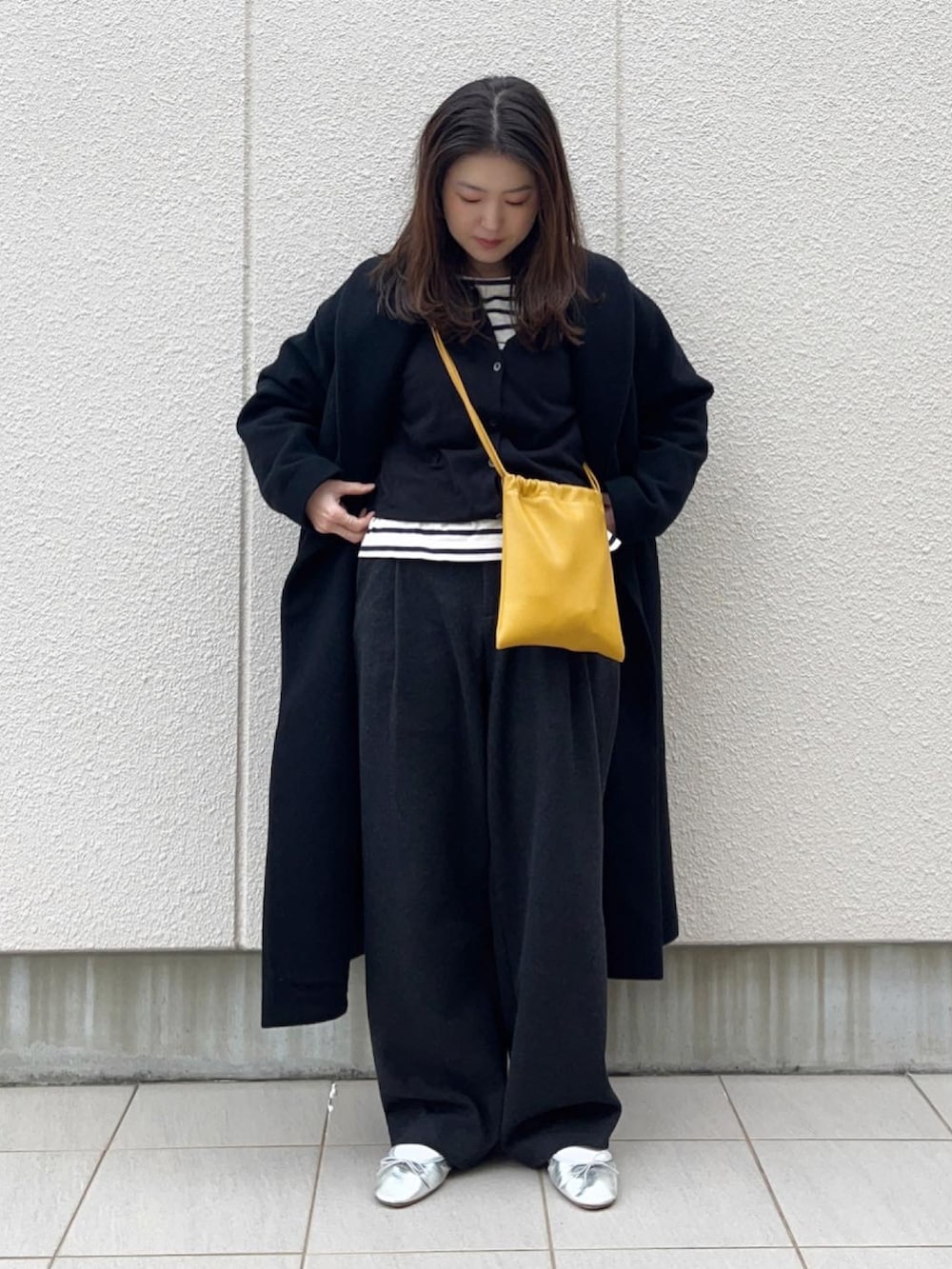 ブラック系のカーディガン/ボレロ、イエロー系のショルダーバッグ、グレー系のパンツを着用したレディースの冬コーディネートの2枚目の写真