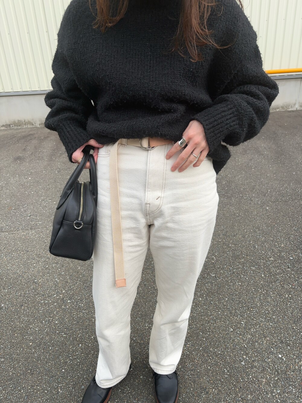 ブラック系のニット/セーター、ホワイト系のデニムパンツ、ホワイト系のベルトを着用したレディースの冬コーディネートの3枚目の写真