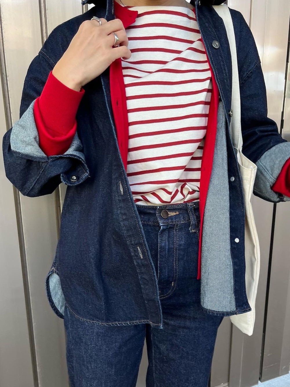 レッド系のトートバッグ、ブルー系のデニムパンツ、ブルー系のデニムジャケットを着用したレディースの秋コーディネートの2枚目の写真