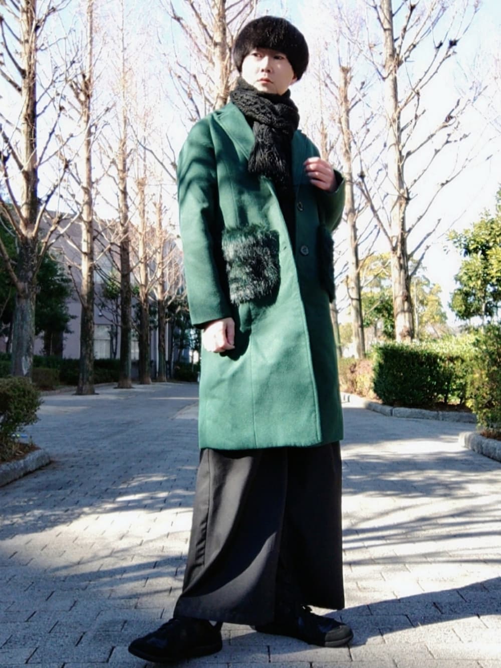 グリーン系のチェスターコート、ブラック系のその他パンツ、ブラック系のスニーカーを着用したメンズの冬コーディネートの2枚目の写真