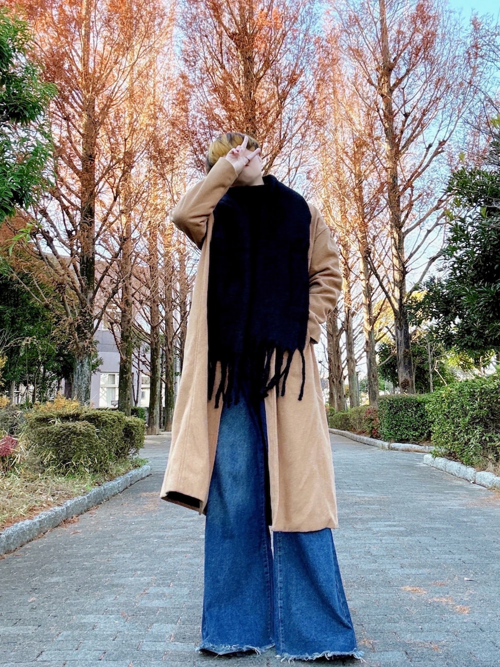 ベージュ系のチェスターコート、ブルー系のデニムパンツ、ブラック系のブーツを着用したメンズの冬コーディネートの2枚目の写真