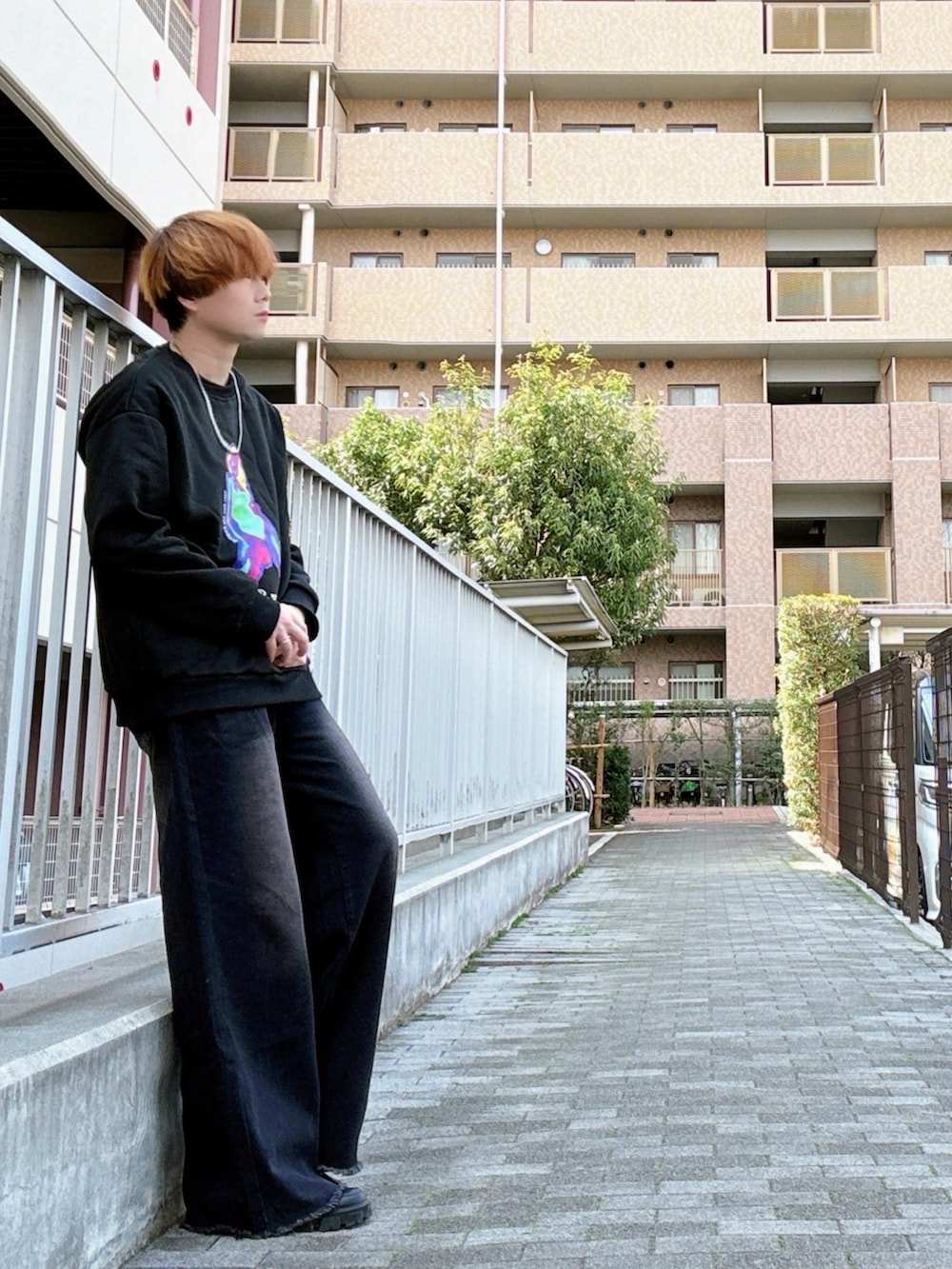 ブラック系のスウェット、ブラック系のデニムパンツ、ブラック系のドレスシューズを着用したメンズの春コーディネートの2枚目の写真