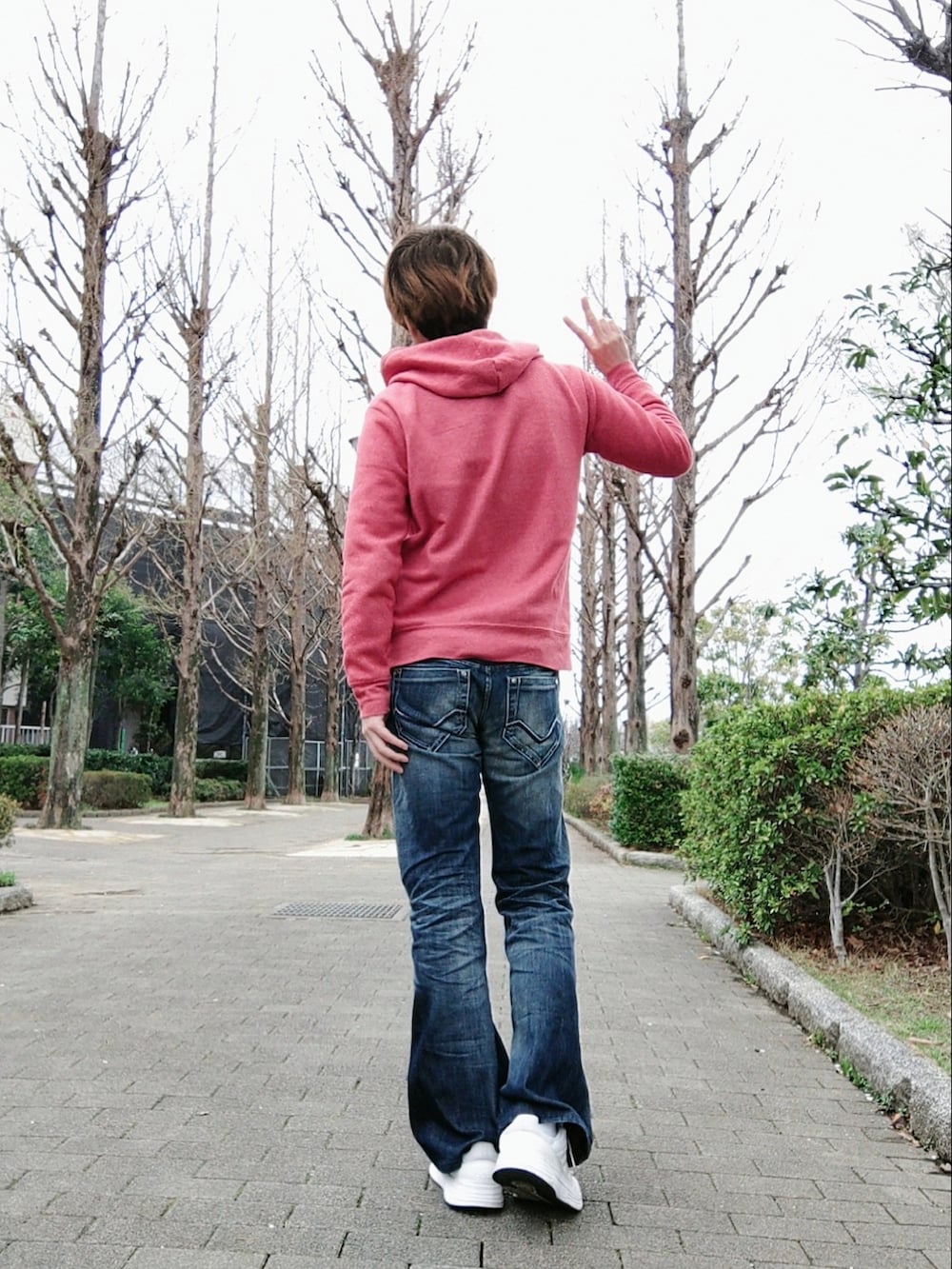 レッド系のパーカー、ブルー系のデニムパンツ、ホワイト系のスニーカーを着用したメンズの春コーディネートの2枚目の写真