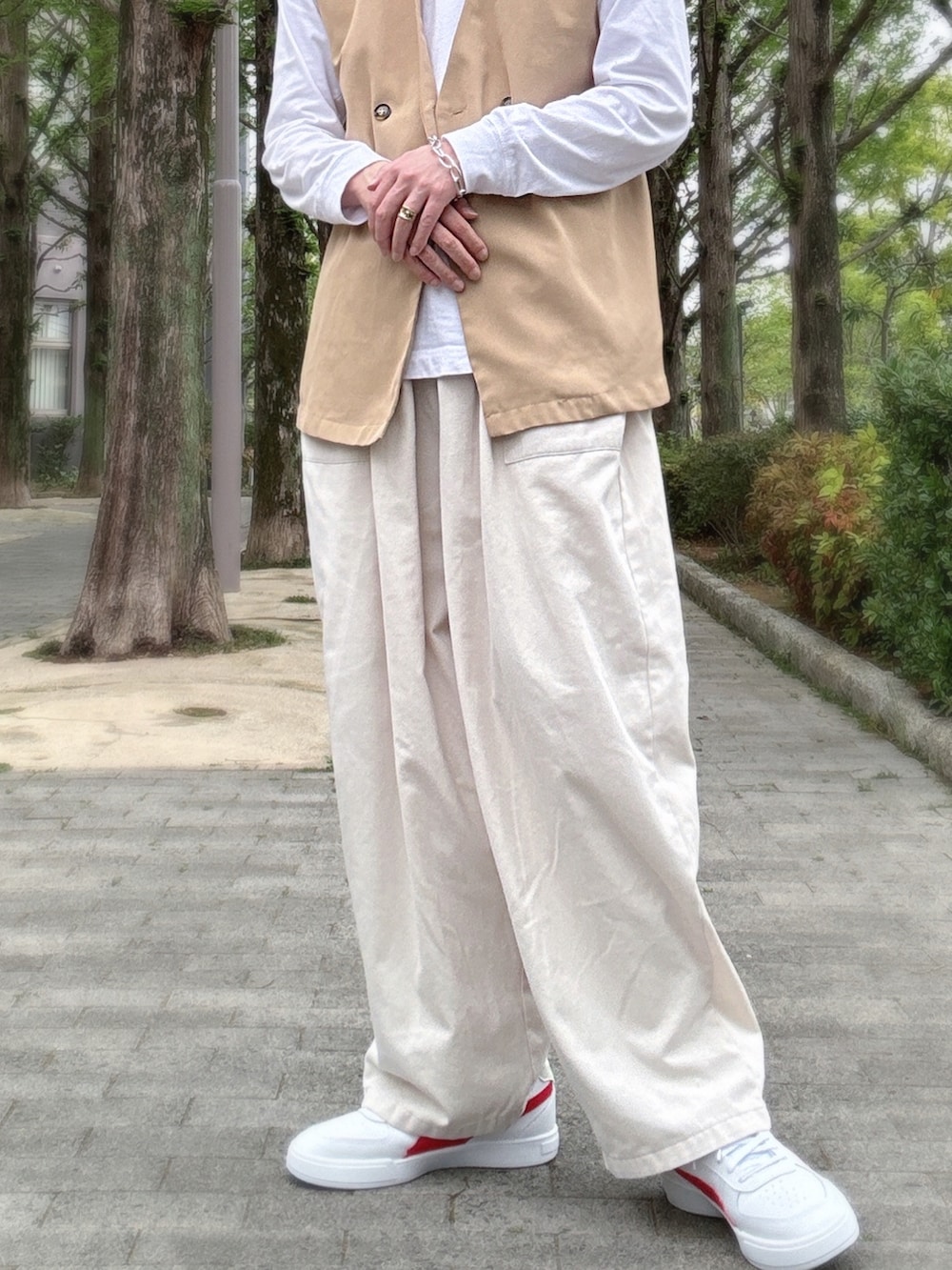ベージュ系のベスト、ホワイト系のその他パンツ、ホワイト系のスニーカーを着用したメンズの春コーディネートの2枚目の写真