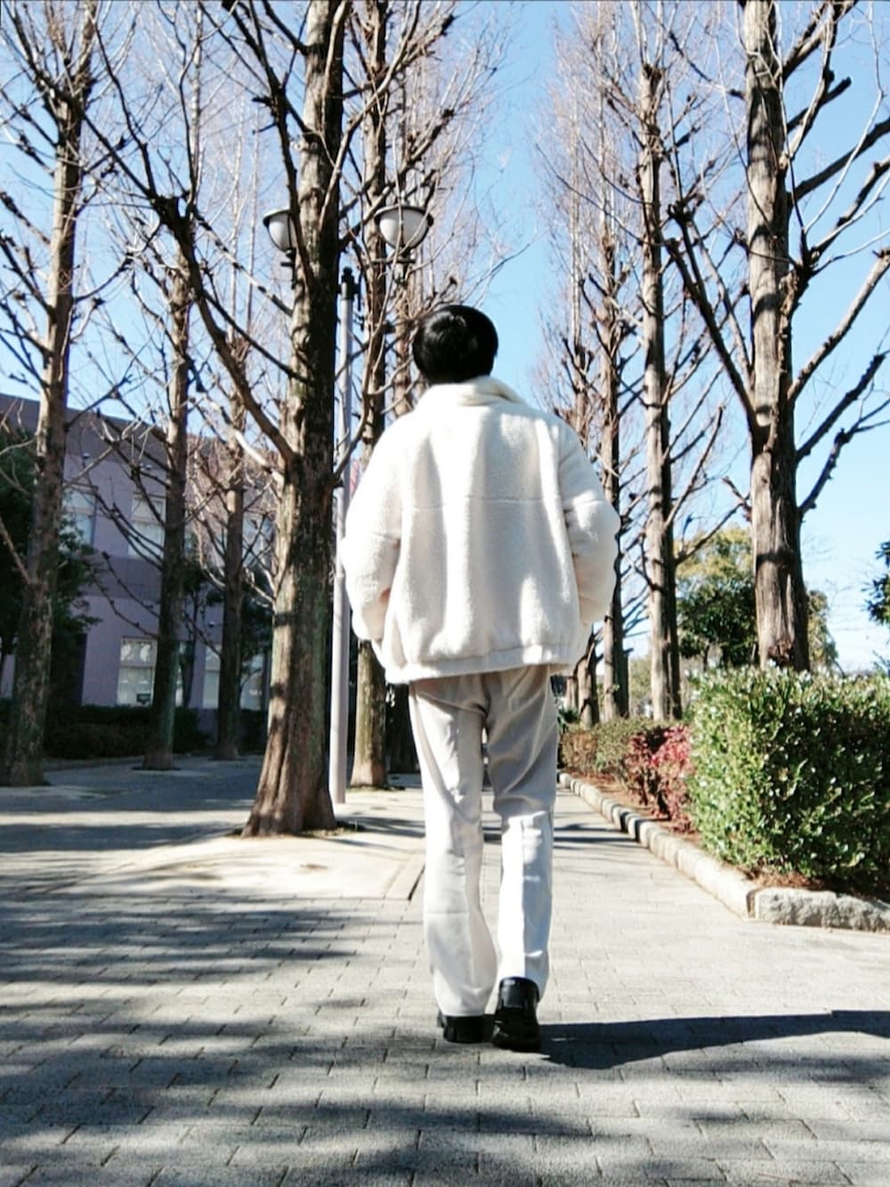 ホワイト系のブルゾン、ホワイト系のスラックス、ブラック系のドレスシューズを着用したメンズの冬コーディネートの3枚目の写真