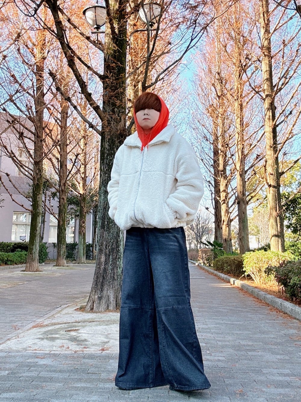 ホワイト系のブルゾン、オレンジ系のパーカー、ブラック系のデニムパンツを着用したメンズの冬コーディネートの2枚目の写真