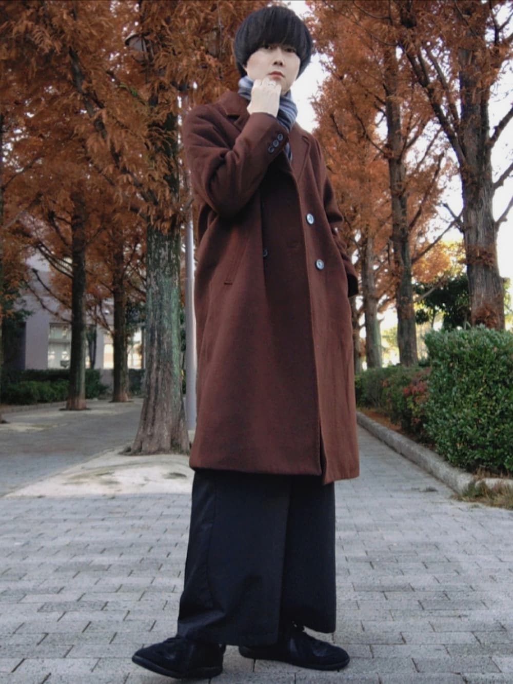 ブラウン系のチェスターコート、ブラック系のその他パンツ、ブラック系のスニーカーを着用したメンズの冬コーディネートの2枚目の写真