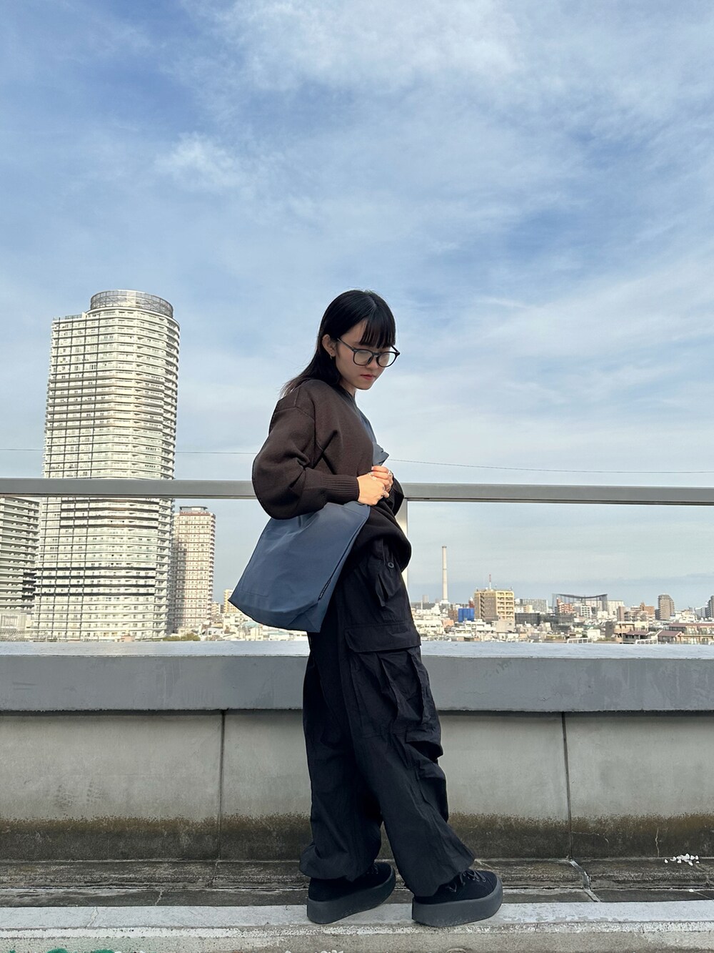 ブラック系のニット/セーター、ブラック系のカーゴパンツ、ブルー系のトートバッグを着用したレディースの秋コーディネートの2枚目の写真