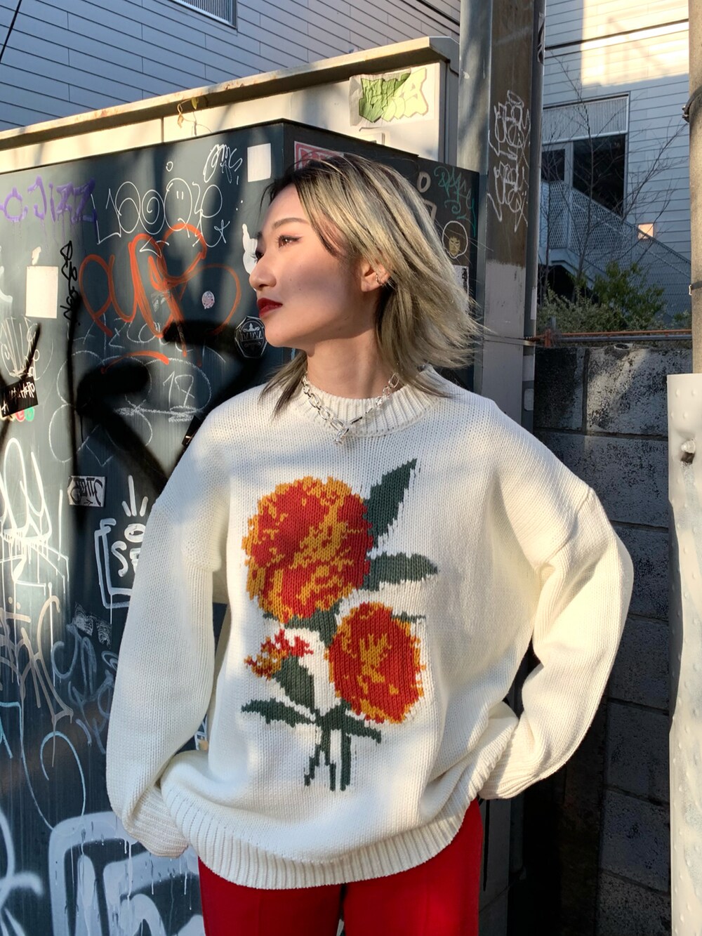 ホワイト系のニット/セーター、レッド系のスラックスを着用したレディースの冬コーディネートの2枚目の写真