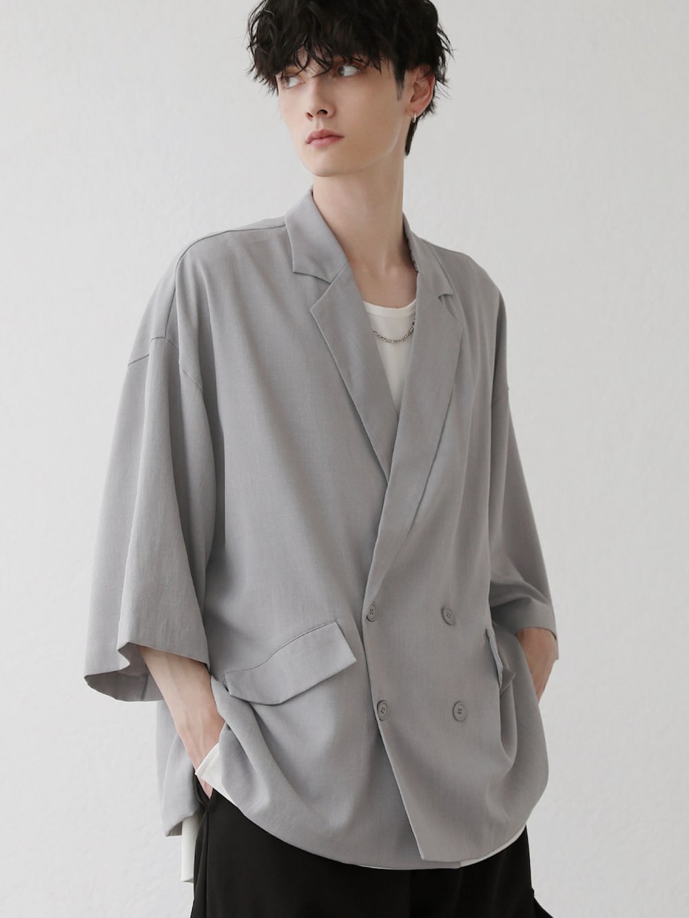 グレー系のテーラードジャケット、ホワイト系のタンクトップ、グレー系のデニムパンツを着用したメンズの夏コーディネートの2枚目の写真