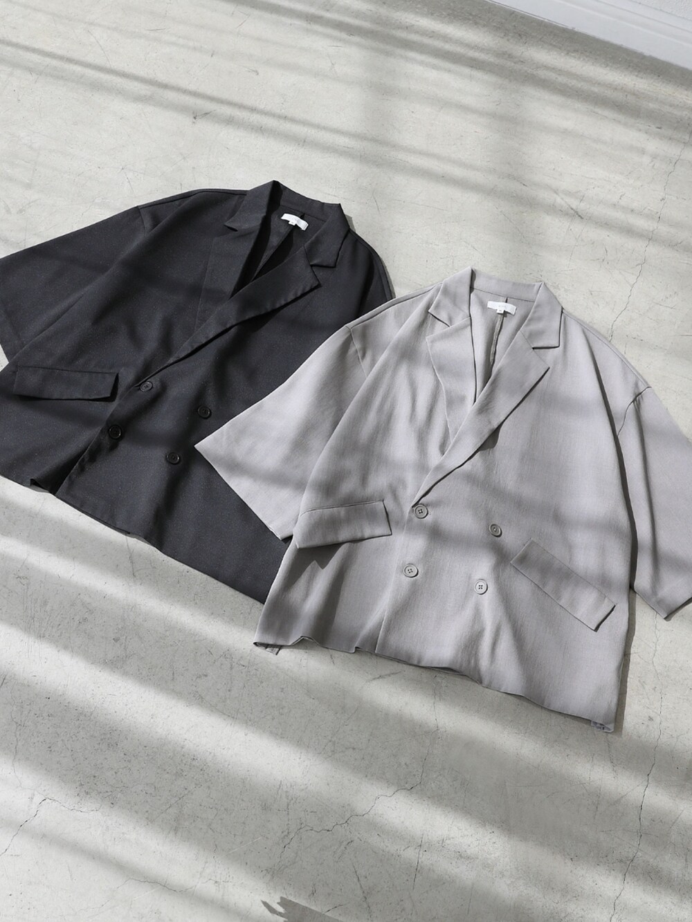 グレー系のテーラードジャケット、ホワイト系のタンクトップ、グレー系のデニムパンツを着用したメンズの夏コーディネートの5枚目の写真