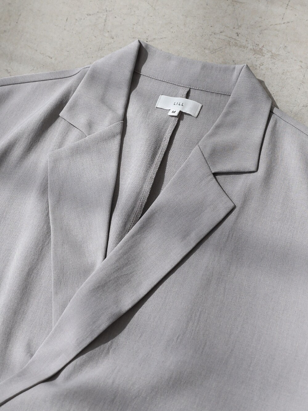 グレー系のテーラードジャケット、ホワイト系のタンクトップ、グレー系のデニムパンツを着用したメンズの夏コーディネートの4枚目の写真