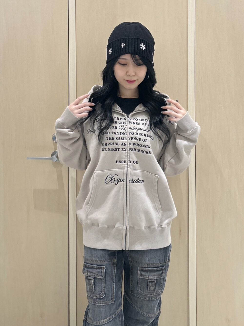 ベージュ系のパーカー、ブラック系のデニムパンツ、ブラック系のハットを着用したレディースの秋コーディネートの4枚目の写真