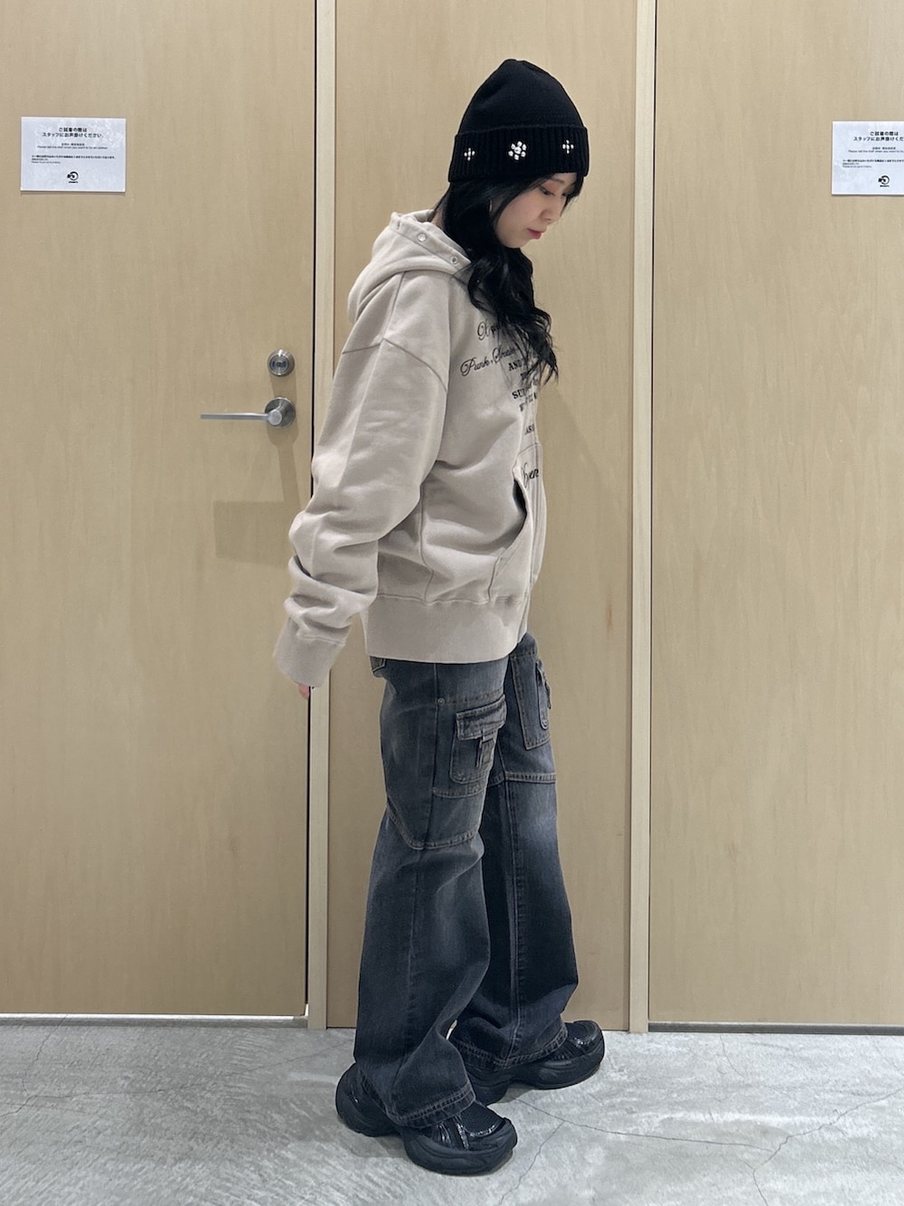 ベージュ系のパーカー、ブラック系のデニムパンツ、ブラック系のハットを着用したレディースの秋コーディネートの2枚目の写真