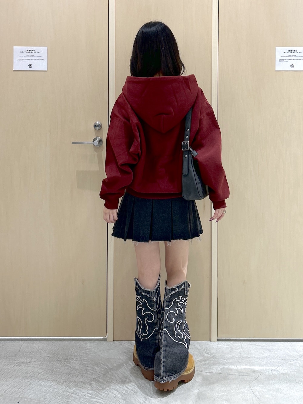 レッド系のパーカー、ブラック系のハンドバッグ、ブラック系のデニムスカートを着用したレディースの秋コーディネートの3枚目の写真