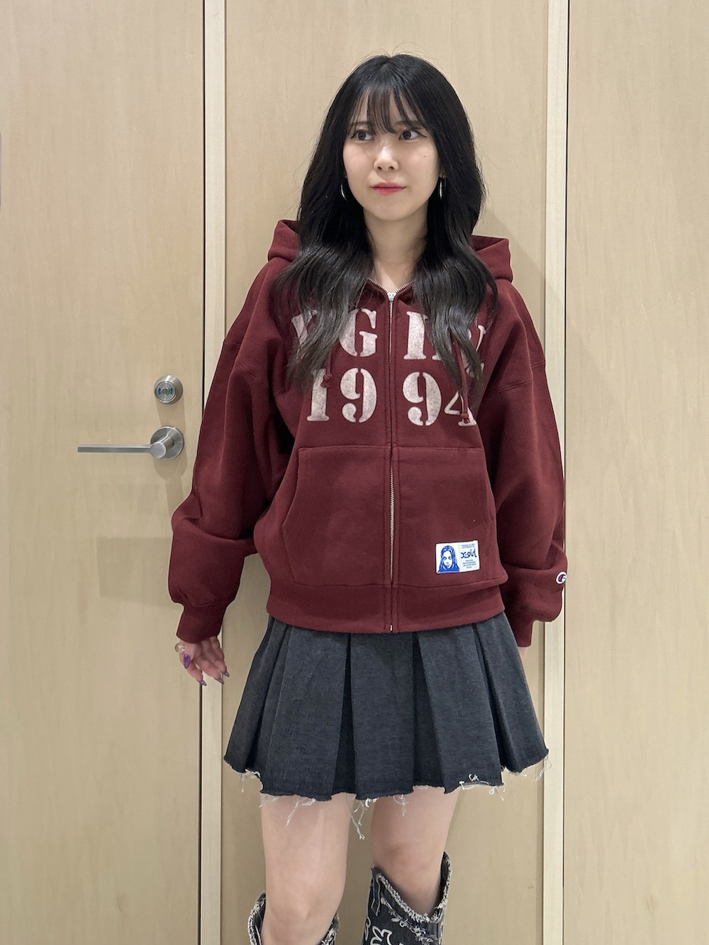 レッド系のパーカー、ブラック系のハンドバッグ、ブラック系のデニムスカートを着用したレディースの秋コーディネートの4枚目の写真