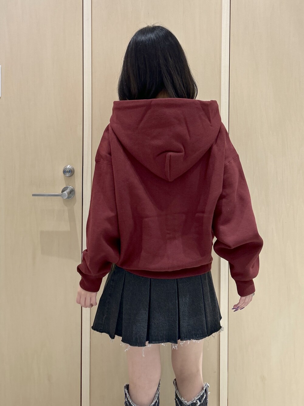 レッド系のパーカー、ブラック系のハンドバッグ、ブラック系のデニムスカートを着用したレディースの秋コーディネートの6枚目の写真