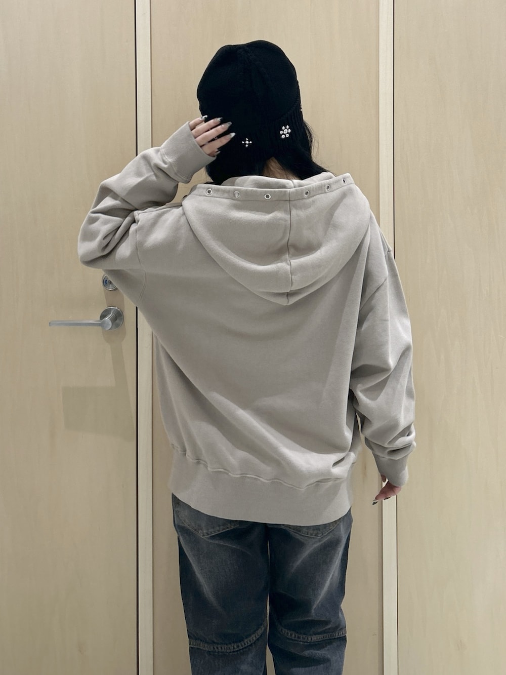 ベージュ系のパーカー、ブラック系のデニムパンツ、ブラック系のハットを着用したレディースの秋コーディネートの5枚目の写真