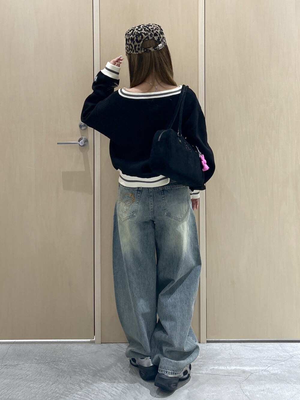 ブラック系のニット/セーター、ブルー系のデニムパンツ、ブラック系のハンドバッグを着用したレディースの秋コーディネートの3枚目の写真