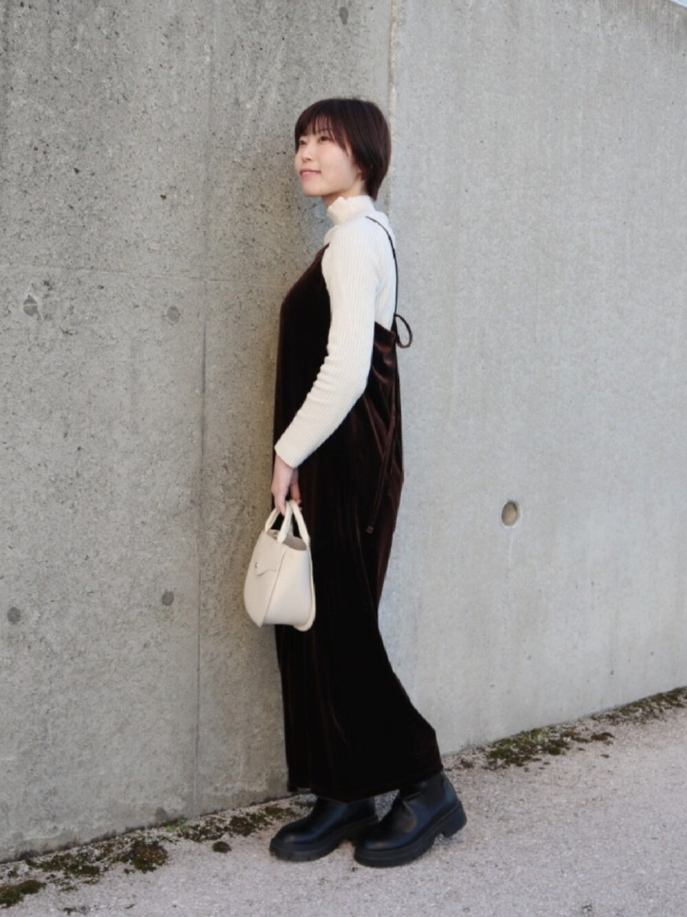 ブラウン系のワンピース、ホワイト系のニット/セーター、ブラック系のブーツを着用したレディースの春コーディネートの2枚目の写真