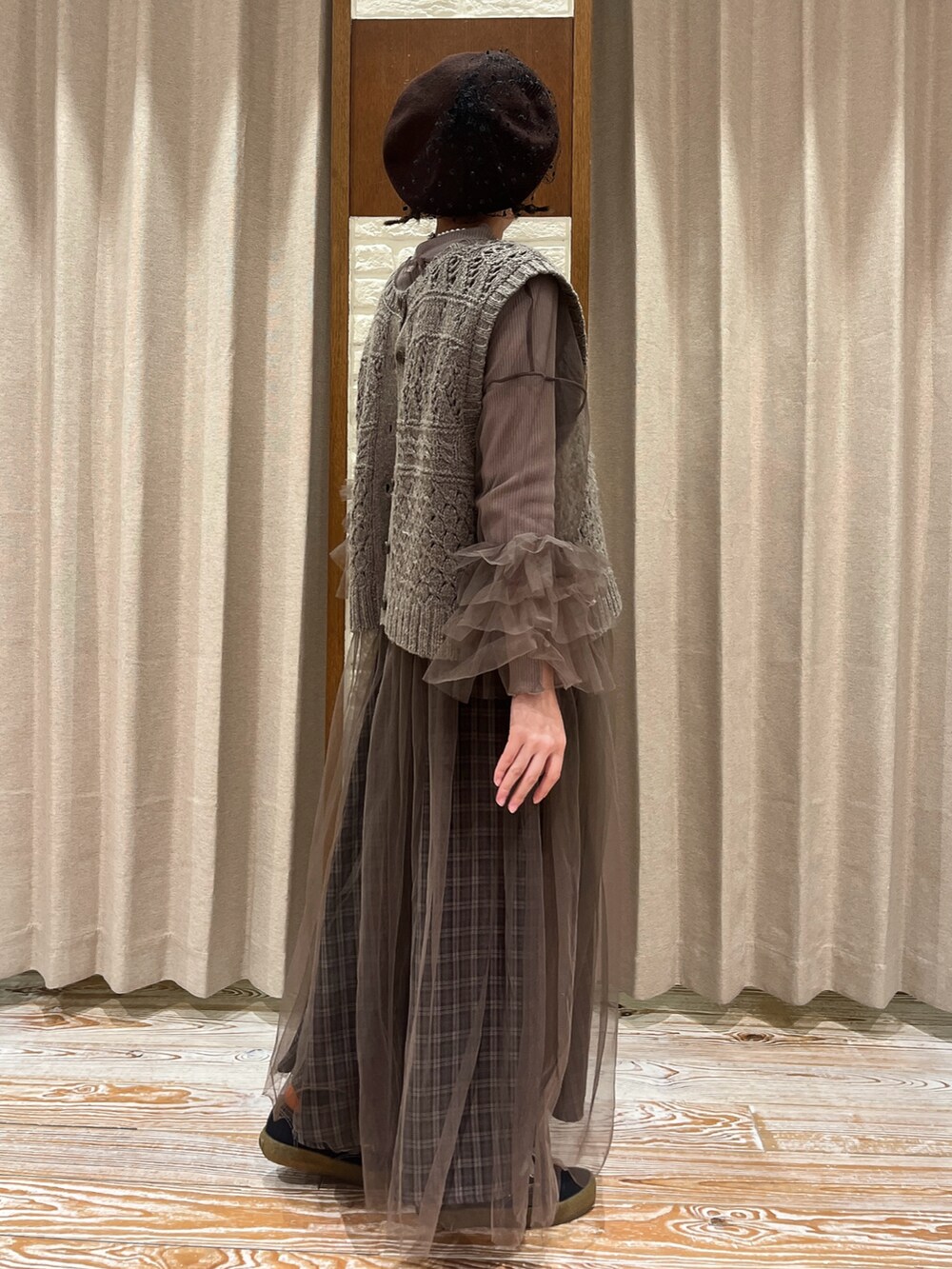 ブラウン系のベスト、ブラウン系のワンピース、グレー系のスカートを着用したレディースの秋コーディネートの2枚目の写真