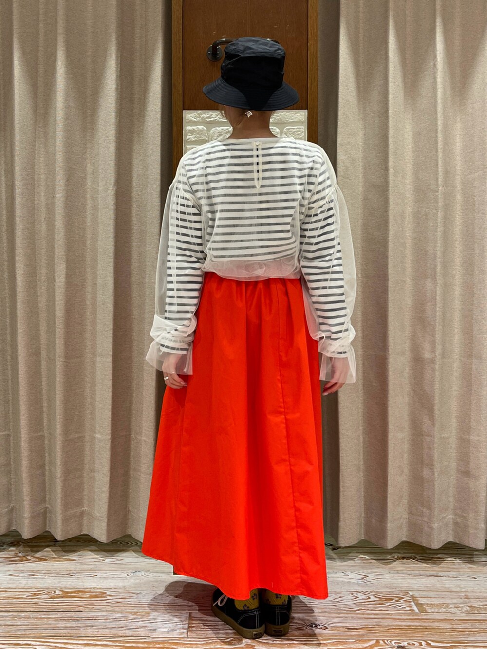 レッド系のスカート、ブラック系のスニーカー、ホワイト系のTシャツ/カットソーを着用したレディースの春コーディネートの3枚目の写真