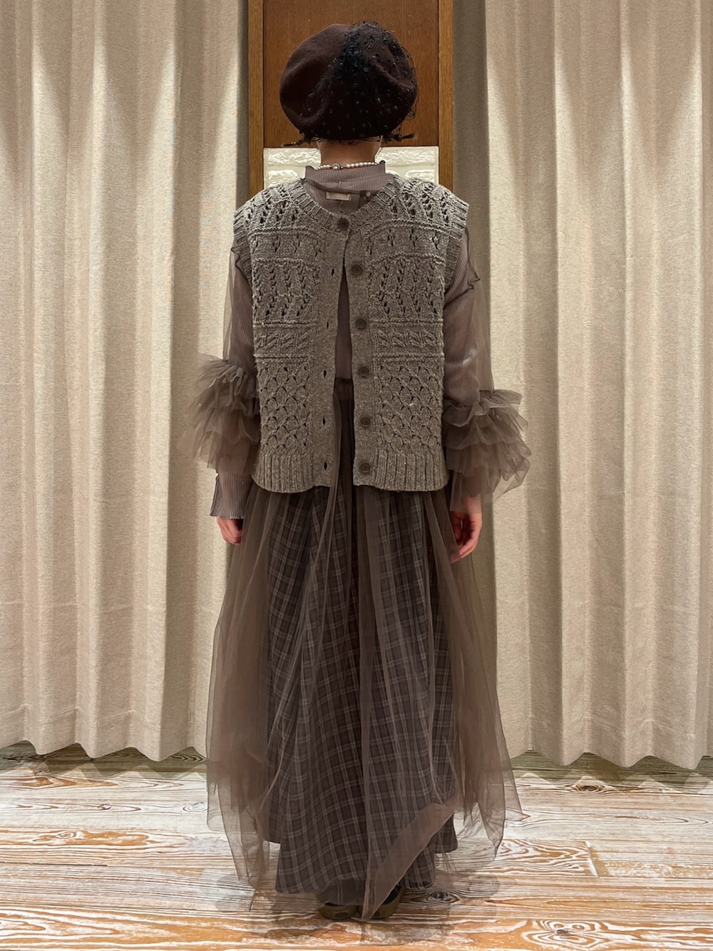 ブラウン系のベスト、ブラウン系のワンピース、グレー系のスカートを着用したレディースの秋コーディネートの3枚目の写真