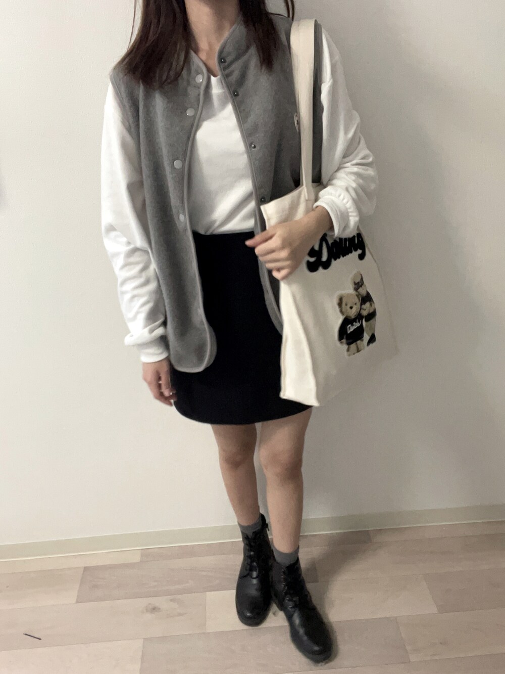 ブラック系のブーツ、ブラック系のスカート、ホワイト系のTシャツ/カットソーを着用したレディースの秋コーディネートの2枚目の写真