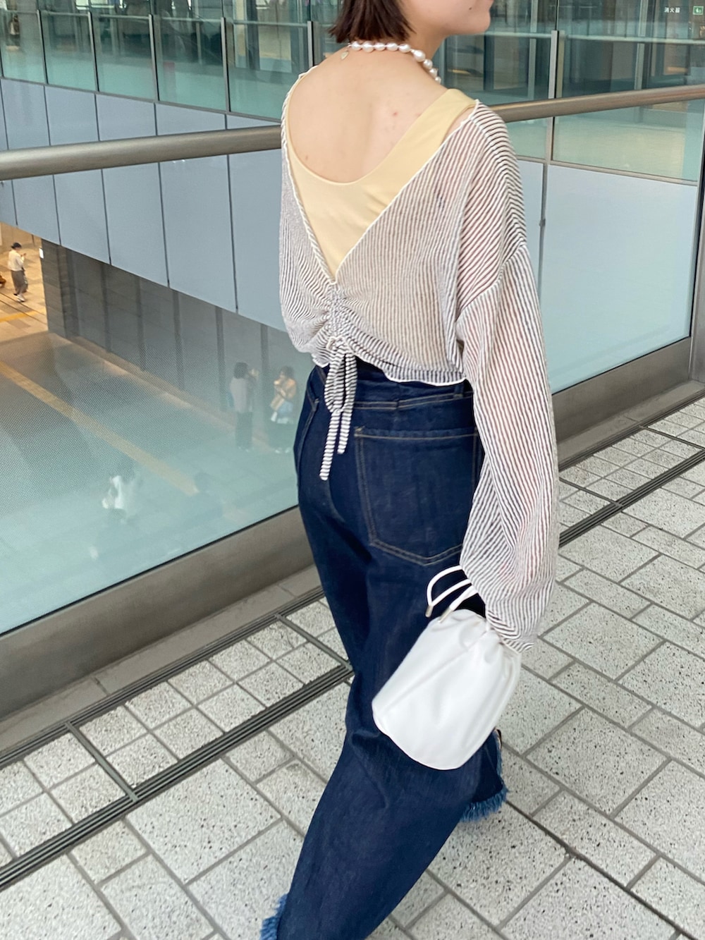 ブルー系のデニムパンツ、ブラック系のキャップ、イエロー系の水着を着用したレディースの春コーディネートの2枚目の写真