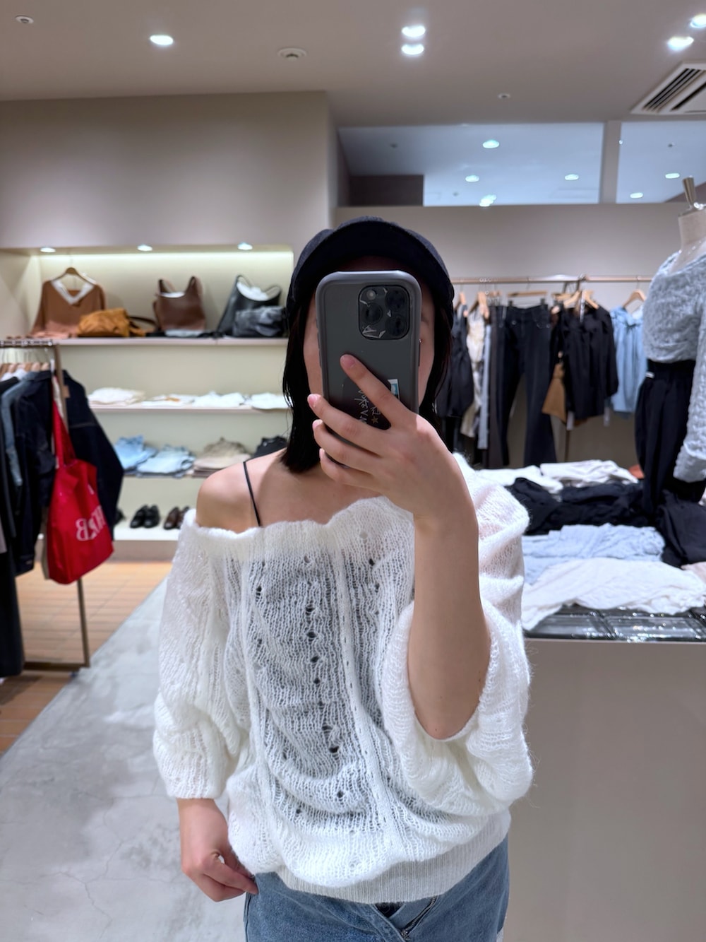 ブルー系のデニムパンツ、ブラック系のキャミソール、ホワイト系のニット/セーターを着用したレディースの秋コーディネートの2枚目の写真