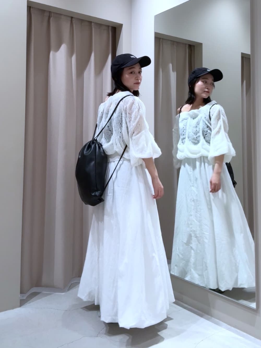 ホワイト系のスカート、ブラック系のバックパック/リュック、ホワイト系のニット/セーターを着用したレディースの秋コーディネートの2枚目の写真