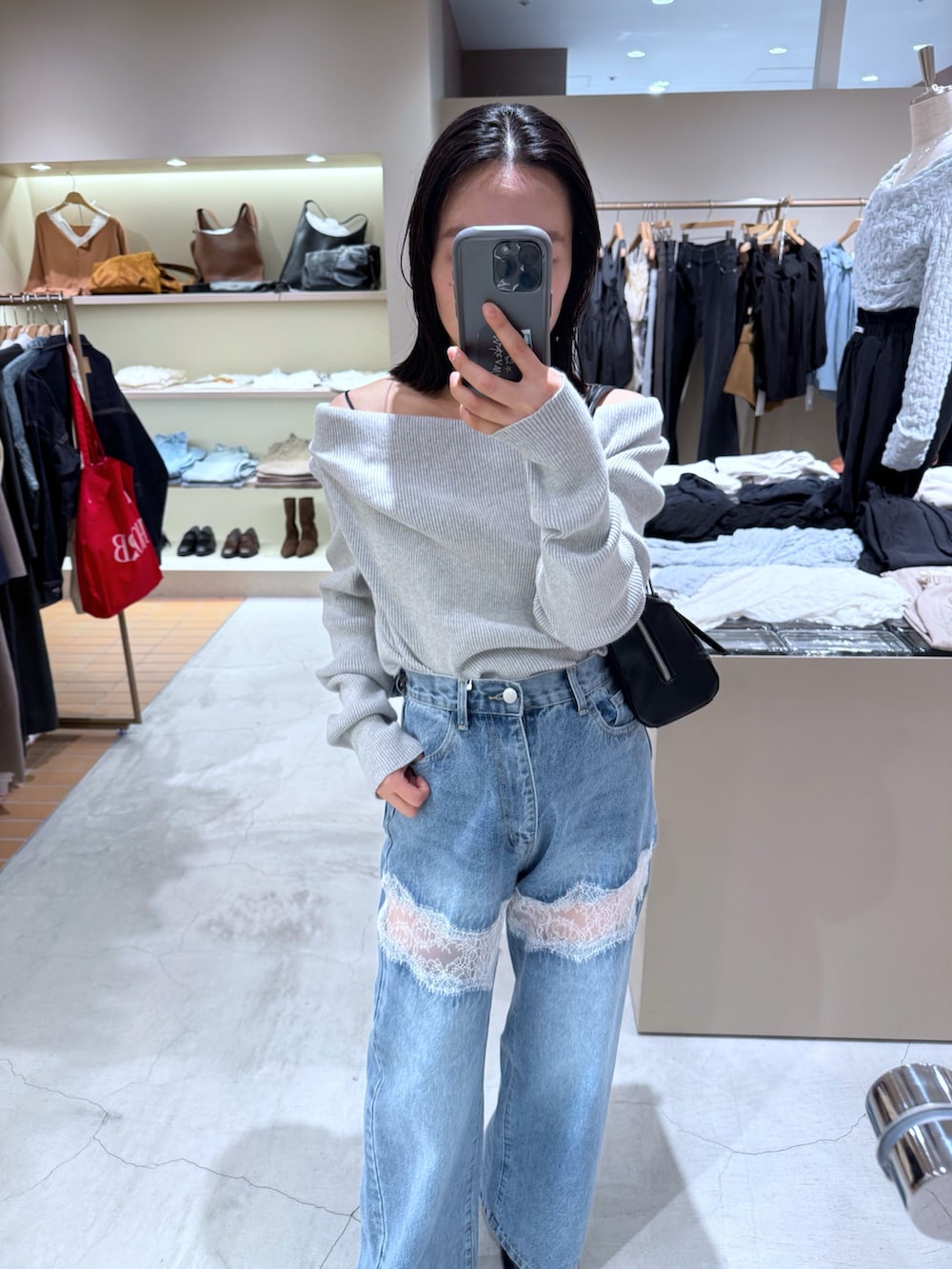 ブルー系のデニムパンツ、グレー系のニット/セーター、ブラック系のボストンバッグを着用したレディースの秋コーディネートの2枚目の写真