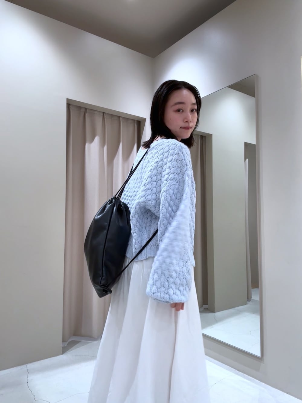 ブラック系のキャミソール、ブルー系のカーディガン/ボレロ、ブラック系のバックパック/リュックを着用したレディースの秋コーディネートの2枚目の写真