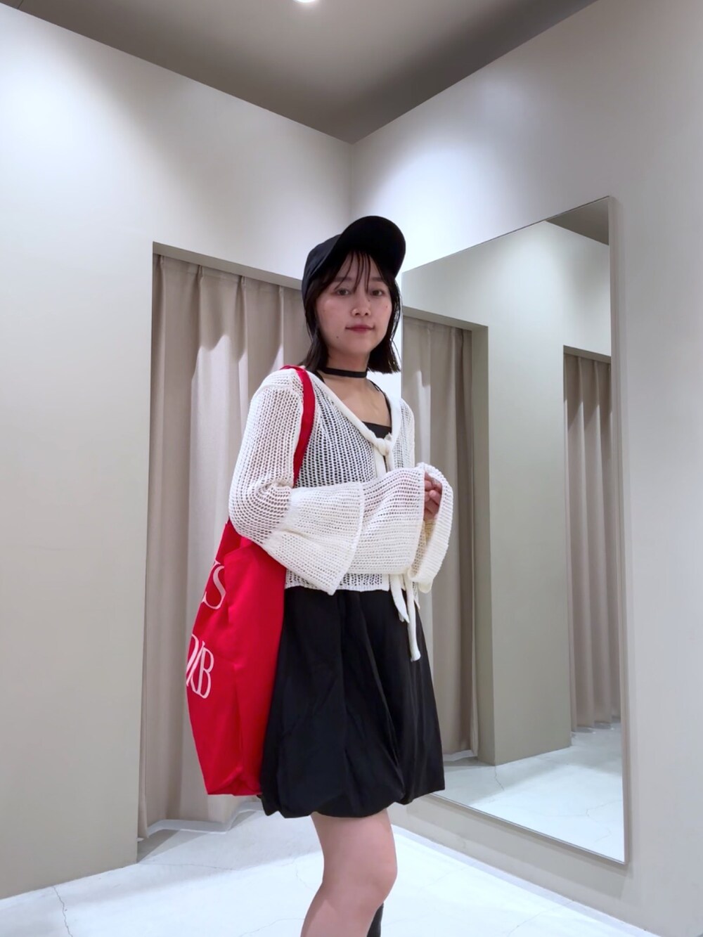 ホワイト系のカーディガン/ボレロ、ブラック系のワンピース、ブラック系のブーツを着用したレディースの秋コーディネートの2枚目の写真