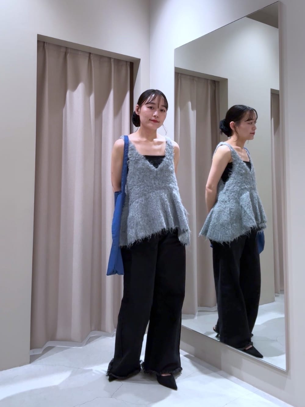 グレー系のベスト、ブラック系のキャミソール、ブラック系のデニムパンツを着用したレディースの秋コーディネートの2枚目の写真