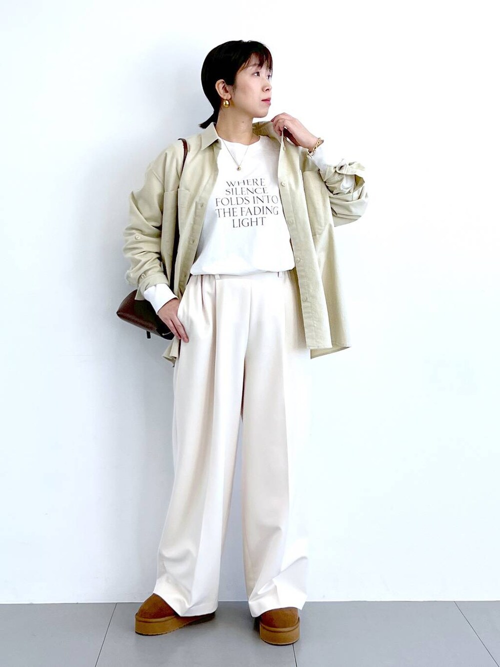 ブラウン系のショルダーバッグ、イエロー系のブーツ、ホワイト系のTシャツ/カットソーを着用したレディースの冬コーディネートの5枚目の写真