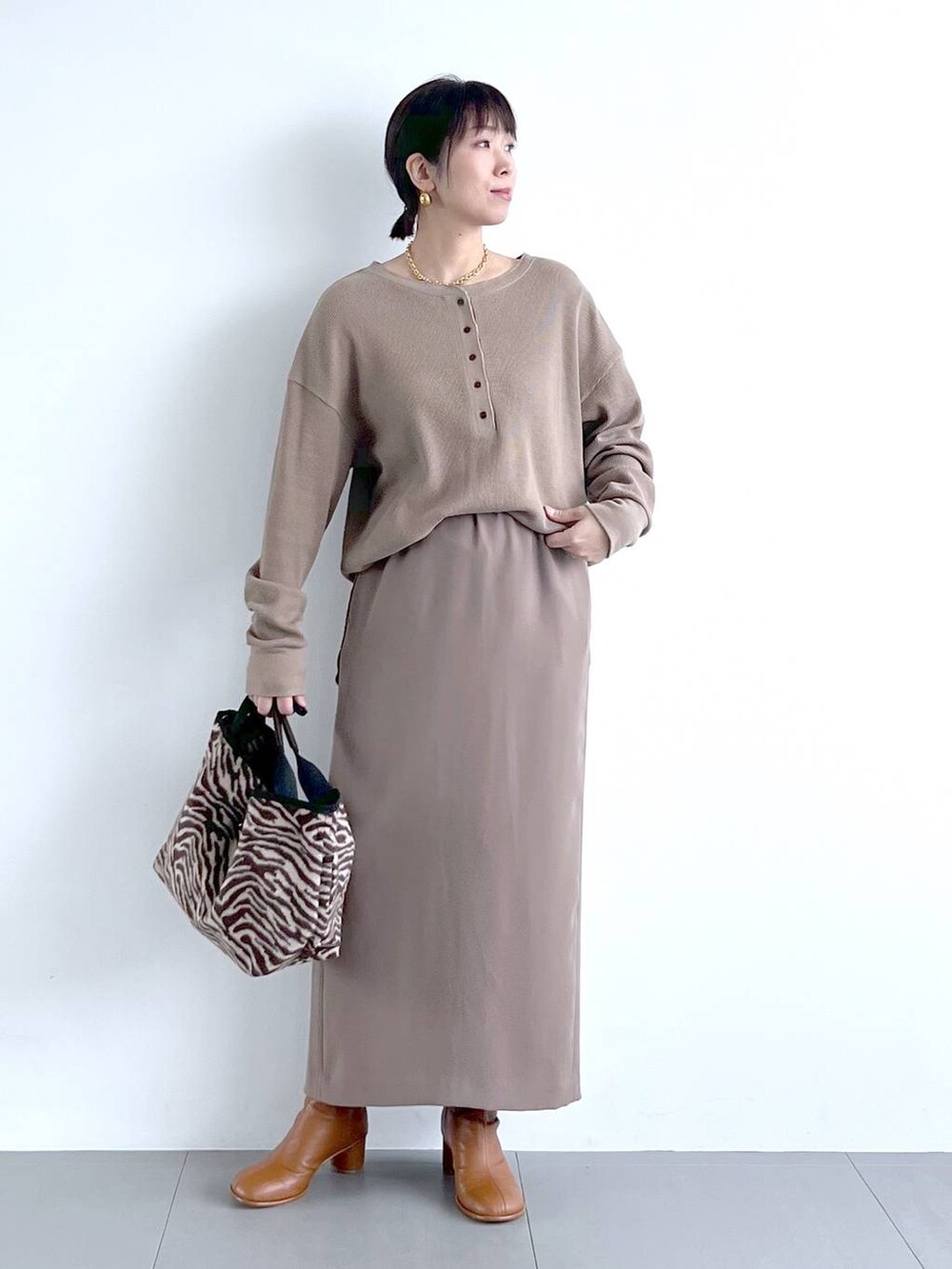 ブラウン系のスカート、イエロー系のブーツ、その他のトートバッグを着用したレディースの秋コーディネートの7枚目の写真