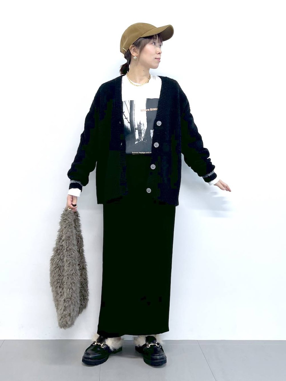 ブラック系のスカート、ブラック系のカーディガン/ボレロ、ブラウン系のハンドバッグを着用したレディースの秋コーディネートの4枚目の写真