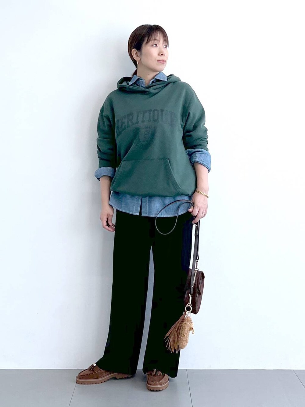 ブラック系のスラックス、グリーン系のパーカー、ブラウン系のショルダーバッグを着用したレディースの秋コーディネートの5枚目の写真