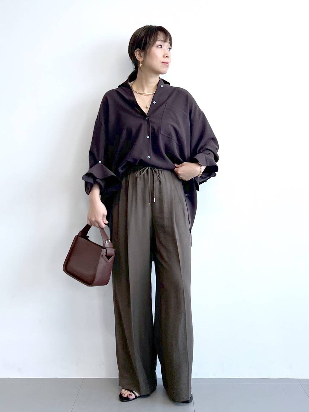 ブラウン系のハンドバッグ、ブラック系のサンダル、ブラウン系のシャツ/ブラウスを着用したレディースの夏コーディネートの3枚目の写真